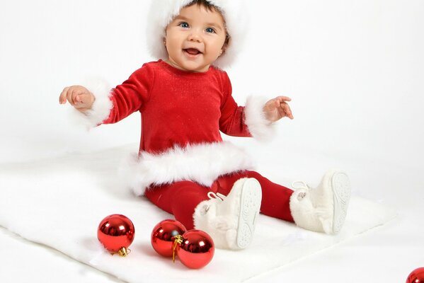 A child in a Red Santa costume on a white rug