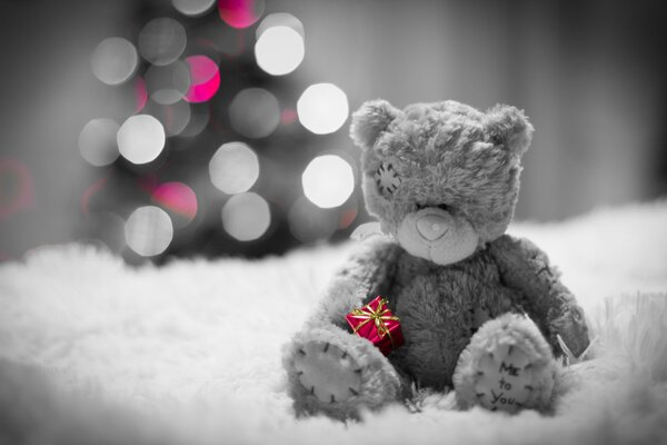 Teddybär sitzt neben dem Weihnachtsbaum