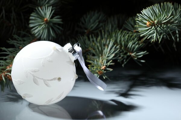 A white ball with a white ribbon on a spruce background