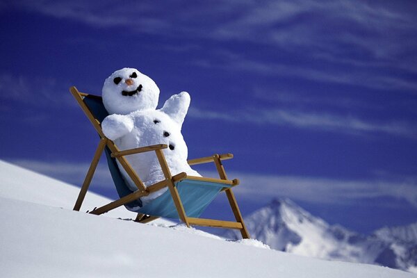 Muñeco de nieve alegre bajo el sol en las montañas