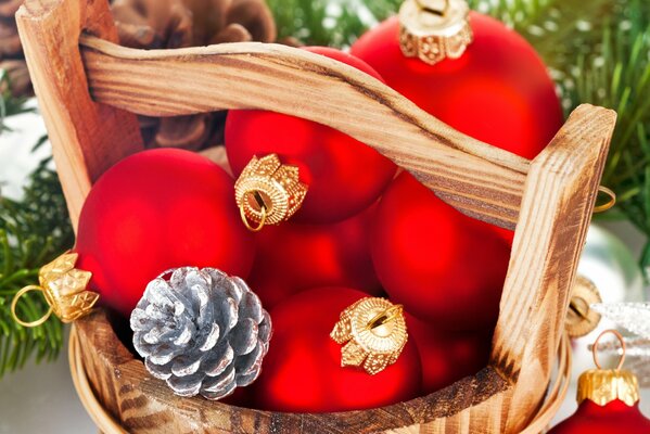 Red Christmas balls and cones lie in a wooden tub