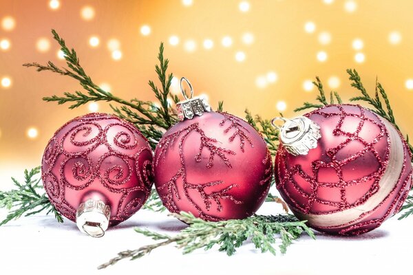 Trois boules roses de Noël avec des branches de genévrier