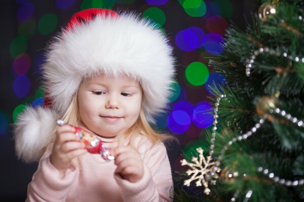 Mädchen entfaltet Süßigkeiten in der Nähe des Weihnachtsbaumes