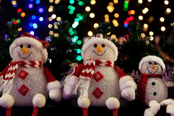 Pupazzi di neve in sciarpe su uno sfondo di ghirlanda con bokeh