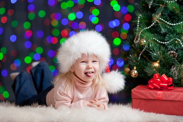 A girl near a gift under the Christmas tree