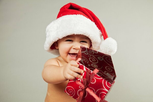 Enfant souriant dans le chapeau du père Noël et avec un cadeau