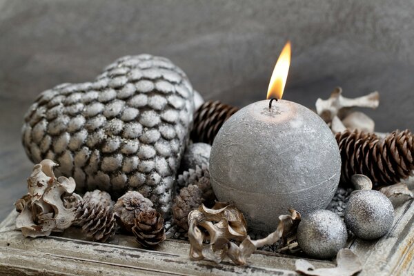 A silver candle, cones and Christmas tree toys are burning