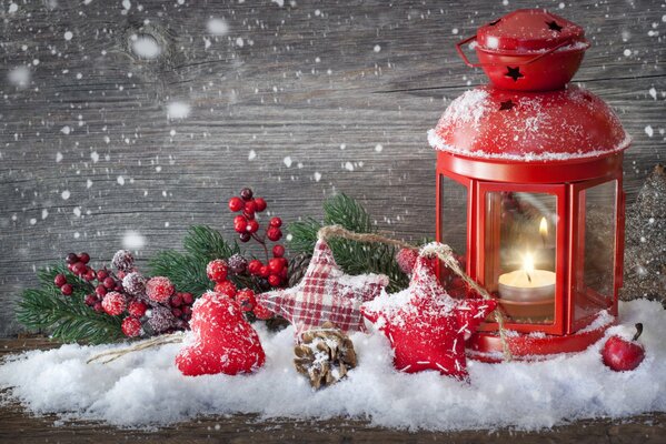 Rote Laterne-Kerzenhalter im Schnee unter Christbaumspielzeugen