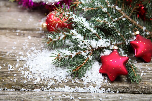 Juguetes de Navidad y ramas de abeto en una mesa de madera en la nieve