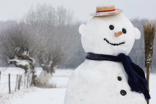 Muñeco de nieve con sombrero con bufanda azul y escoba