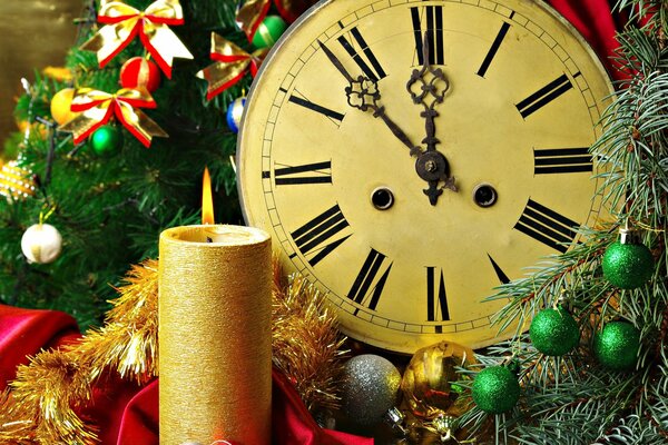 Weihnachtskerze und Uhr in Neujahrsdekoration aus Tannenzweigen in bunten Bögen und Kugeln