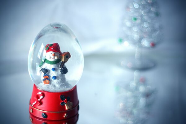 Snowman s glass ball on a glass table