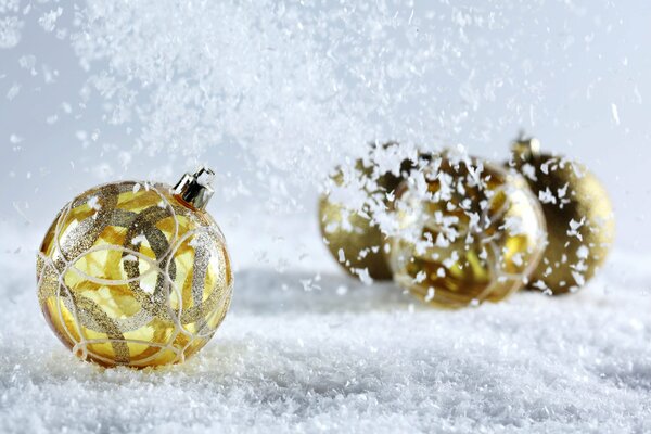 Goldene Christbaumkugeln im Schnee