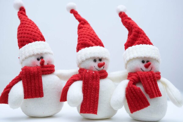 Three snowmen in red scarves and hats