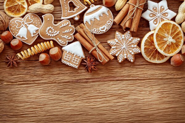 Christmas cookies with white icing, cinnamon sticks and dried oranges on a wooden table