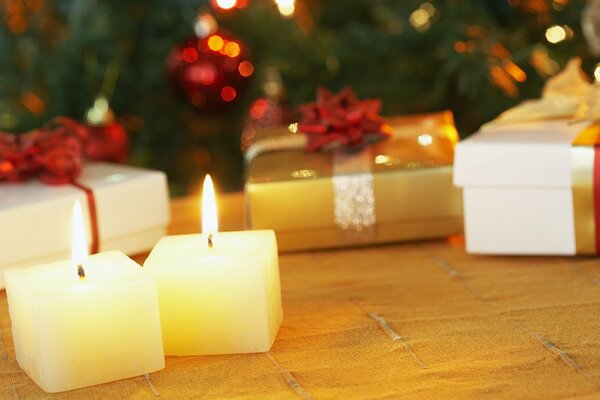 Płonące małe świeczki przy prezentach pod choinką