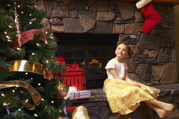 Маленькая девочка в желтой юбке сидит у камина