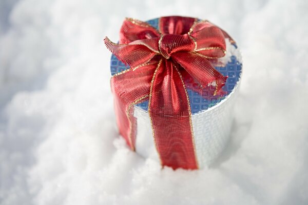 Weihnachtsgeschenk mit roter Schleife im Schnee