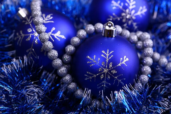 Новогодние синие шары украшенные серебристыми снежинками в синей мишуре
