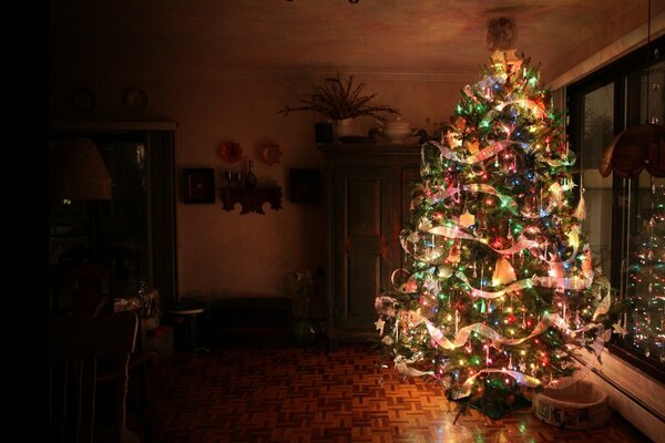 Die Nacht. Weihnachtsbaum mit glühenden Girlanden in der Wohnung