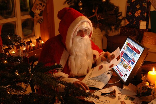 Père Noël derrière un ordinateur portable dans une chambre confortable