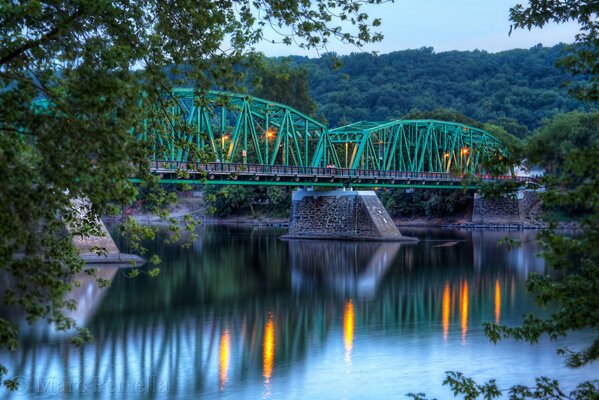 Green bridge in lights on the river