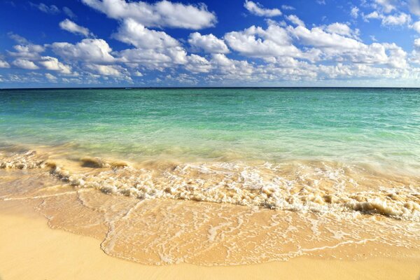 Spiaggia di sabbia con onde blu e belle nuvole