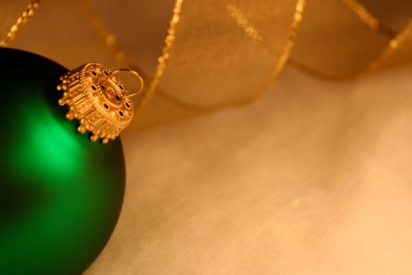 Grünes Spielzeug am Weihnachtsbaum mit goldenem Aufhänger