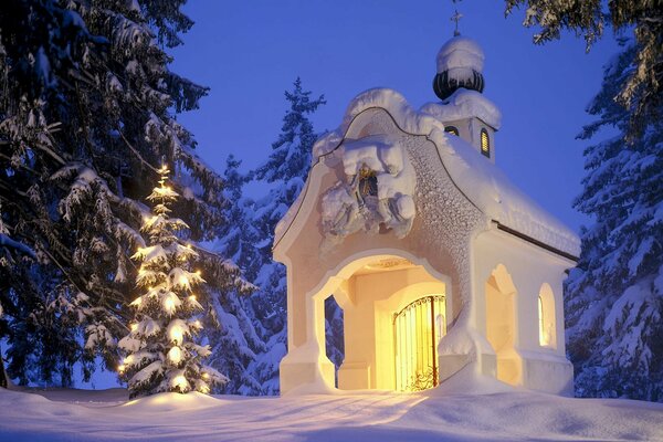 Albero di Natale con ghirlanda vicino alla cappella in inverno