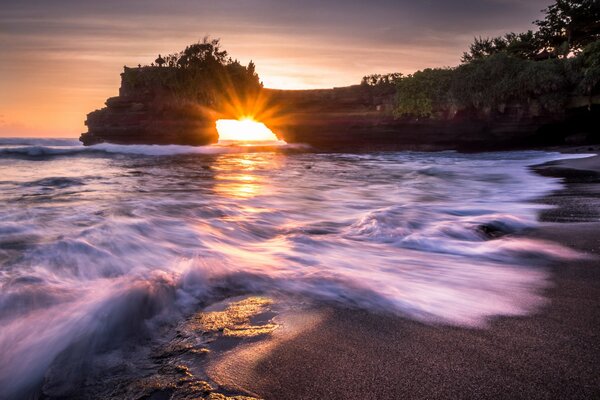 Les rayons du soleil à travers la roche sur le rivage