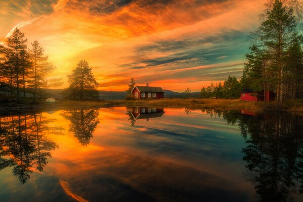 Maison reflétant dans le lac sur fond de beau coucher de soleil