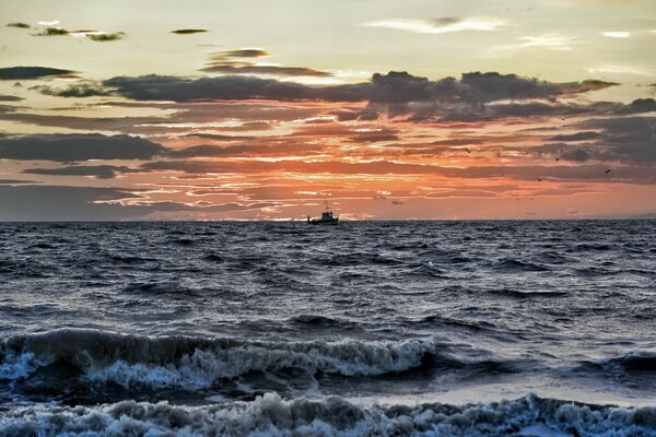 A ship on the background of a sunset in a raging sea