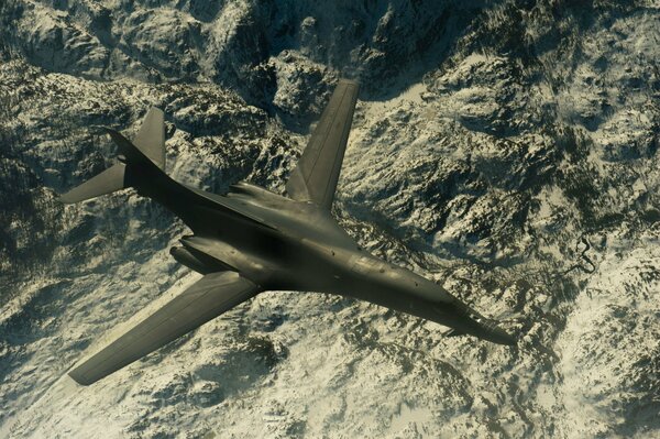 A supersonic b-1b strategic bomber is flying high above the ground