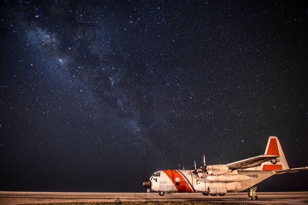 Aereo da trasporto militare Hercules sull aerodromo sullo sfondo del cielo notturno stellato