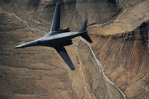 Naddźwiękowy szary bombowiec strategiczny b-1B leci nad krajobrazem