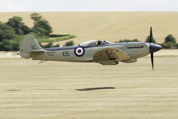 Brytyjski myśliwiec z II wojny światowej leci nad polem