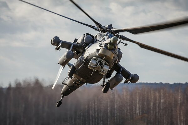 A military helicopter flies over the forest extinguishes a fire