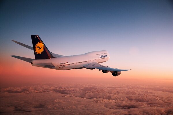 Flugzeug in der Luft bei Sonnenuntergang über den Bergen