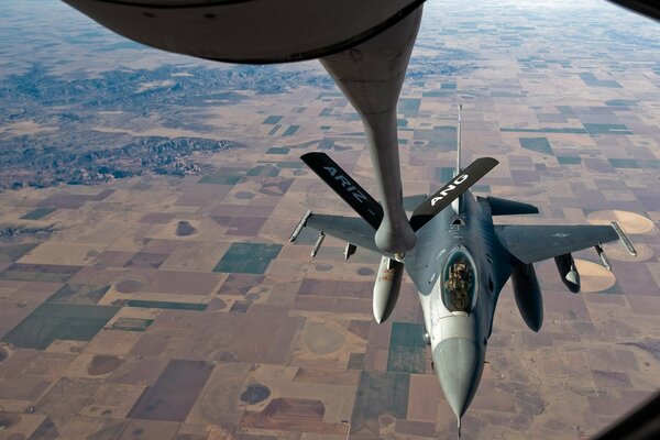 Refueling a fighter in the air over the fields