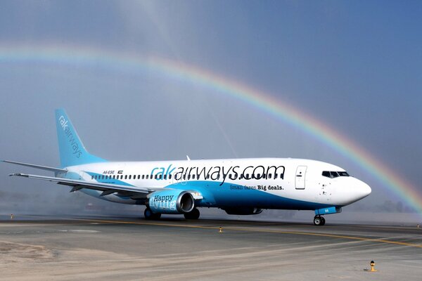 Image of a Boeing at an airfield with a beautiful rainbow