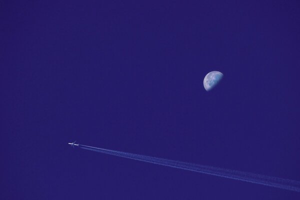 Un avion de passagers dans le ciel survolant la lune laisse derrière lui une trace d inversion
