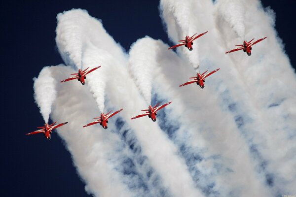 Colas blancas de humo detrás de aviones rojos en el espectáculo aéreo