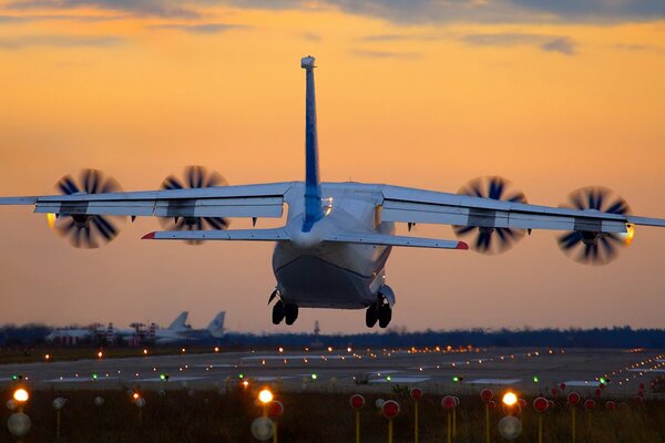 Atterraggio di un aereo al tramonto. Le luci della pista sono accese