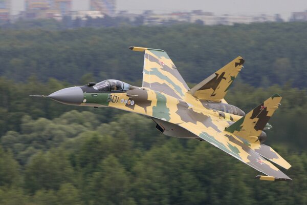 Picture of a su-35 plane flying over a forest