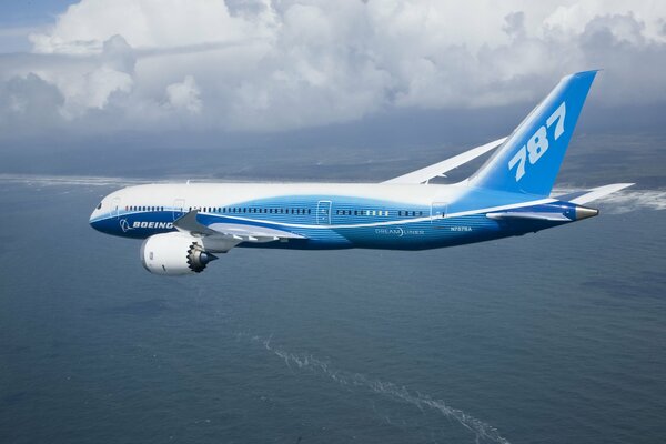 The Boeing plane flies over the sea against the background of clouds