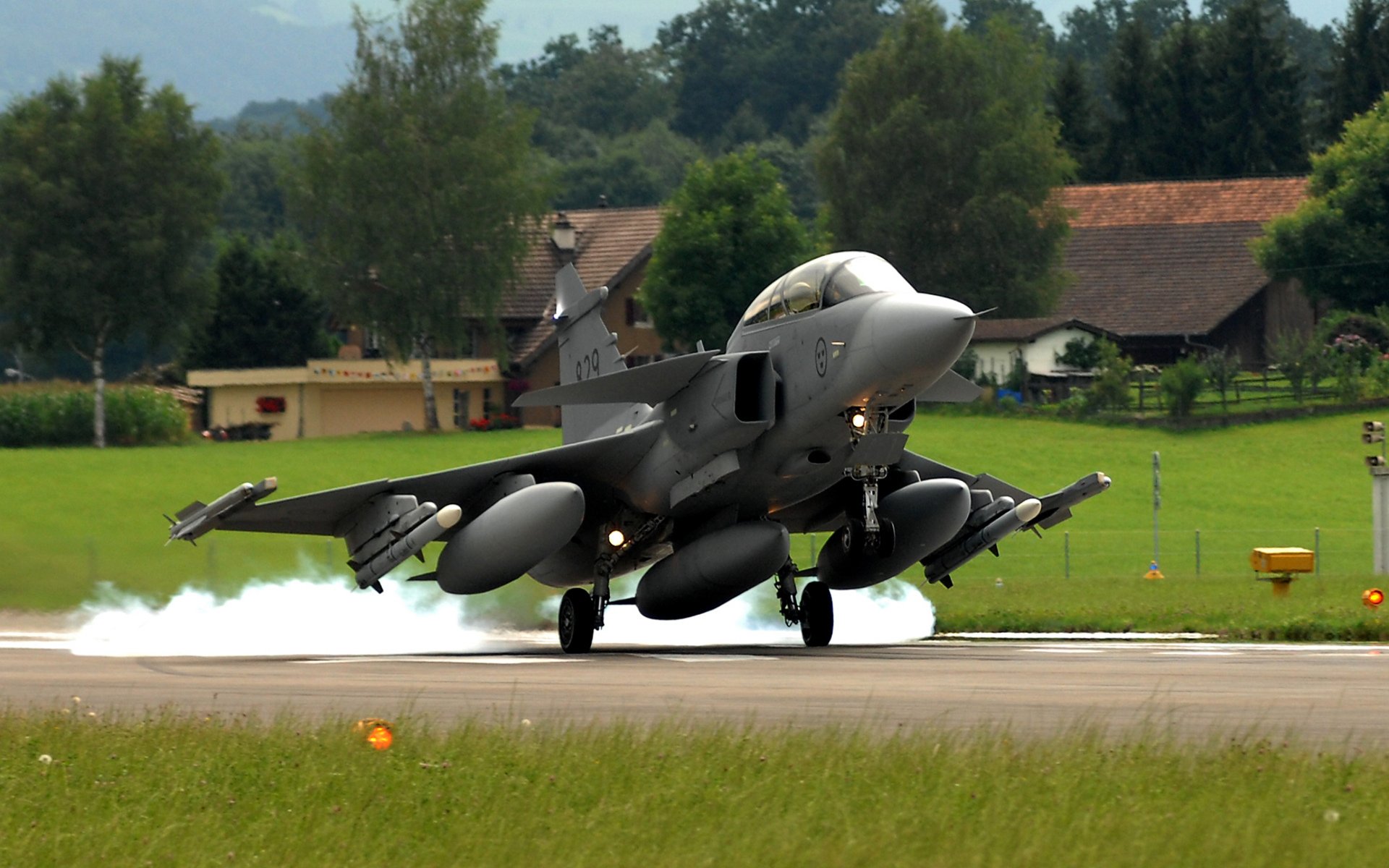 flugzeug saab jas 39 gripen schwedisch mehrzweck kämpfer vierte generation start foto flugplatz streifen gras bäume häuser