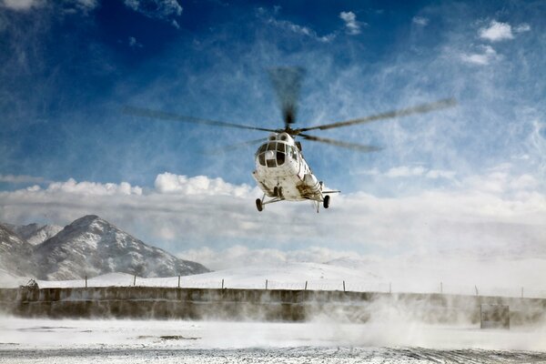 The helicopter is going to take off, raising whirlwinds of snow