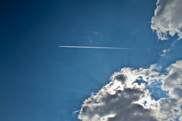 След от самолёта в голубом небе с облоками