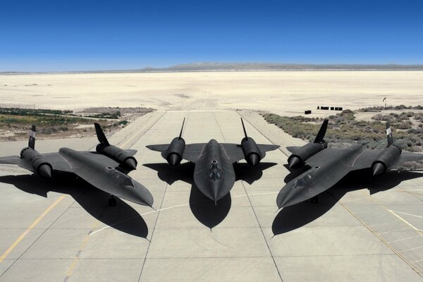 Three planes on the runway in the middle of the desert