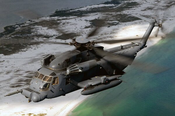 Grey helicopter flying over the sea